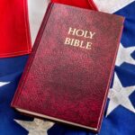 A closeup photograph of a Holy Bible on an American Flag.